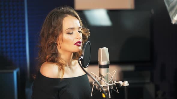 Beautiful sexy young woman singing. Female vocal. Professional recording studio.