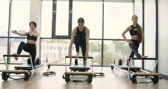 Three Women Doing Pilates on a Reformer Bed