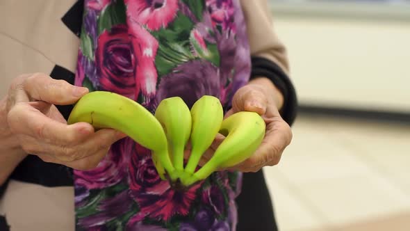 Close-up Grandmother of Eighty Years Buys Fresh Bananas in the Supermarket