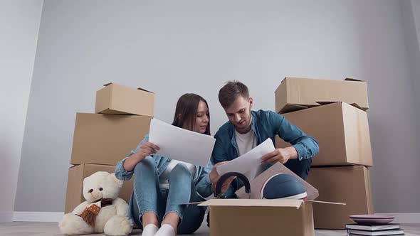 Happy Smiling Couple which Sitting on the Floor and Discussing Interier's Design