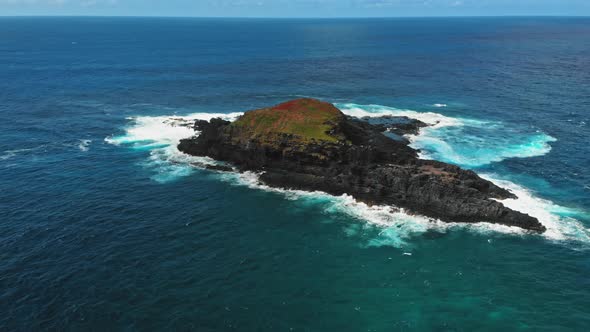 Time lapse drone shot of a rock and foaming waves washing over the ledge in Kauai, Hawaii, USA