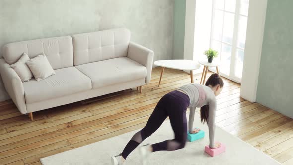 Young Woman Is Making Push-ups From Blocks in Living Room at Home, Top View.