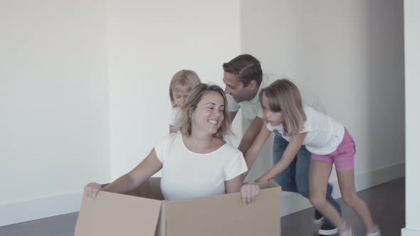 Cheerful Dad and Two Daughters Dragging Box with Happy Mother