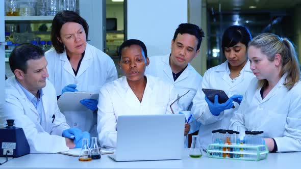 Team of scientist discussing over a laptop 4k