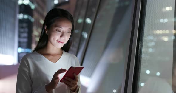 Woman use of mobile phone at business district at night