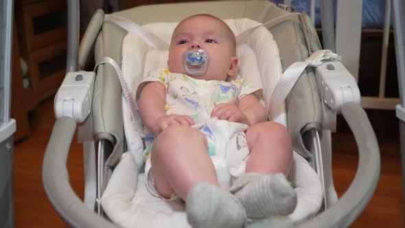 Baby Swings in an Electronic Swing Cute Little Baby Boy Lying in Electric Rocking Chair