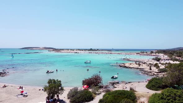 Aerial of Elafonisi bay and beach, tourists, boats and wind surfers, drone