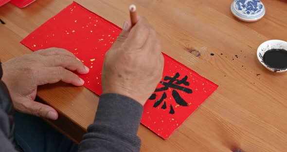 Man write on red paper in chinese for lunar new year, word means luck