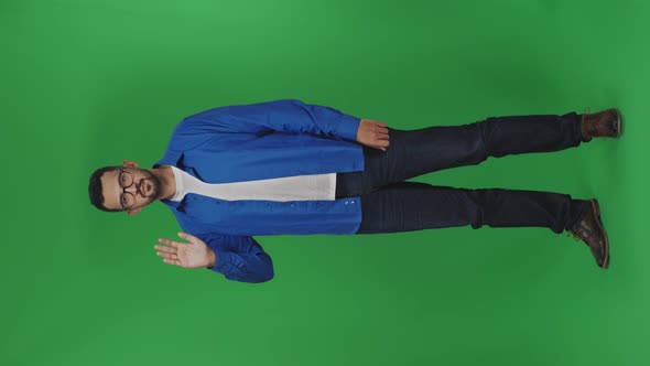 An Attractive Young Man is Waving His Hand Doing Hello Gesture Isolated Over Green Ackground in