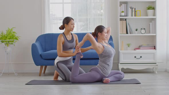 Yoga trainer helping asian woman doing yoga exercise One Legged King Pigeon pose