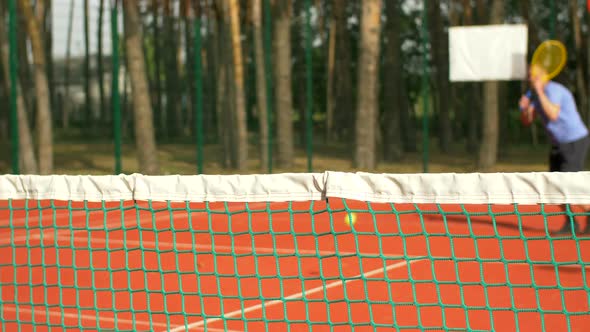 Tennis Player Hitting Ball in Tennis Net