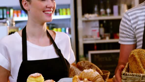 Waiter and waitress holding a basket of bread and croissant