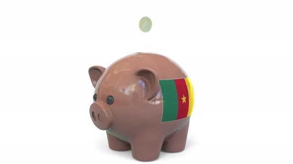 Putting Coins Into Piggy Bank with Flag of Cameroon