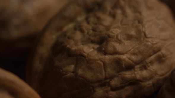 Cinematic, rotating shot of walnuts in their shells on a white surface