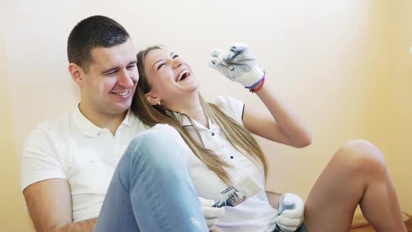 Young Couple Taking a Break From Renovating and Laughing Sitting on the Floor