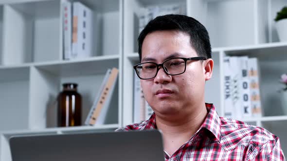 Portrait Asian glasses man looking to screen monitor with stressed face at home office