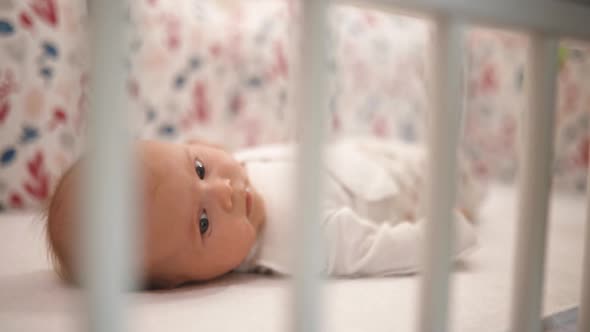 Toddler Lies in Crib Looking Up at Home