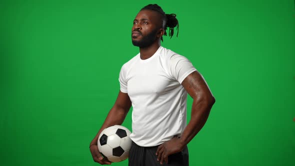 Sweating Tattooed Footballer with Ball Standing at Chromakey Background Looking Away