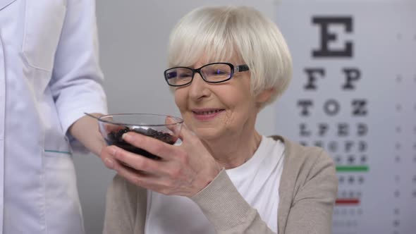 Ophthalmologist Giving Blueberries to Retired Female Patient, Organic Vitamins