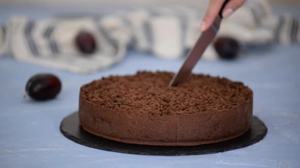 Cutting Homemade Shortbread Chocolate Cake with Plums