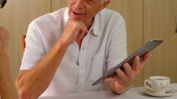 Senior man with digital tablet interacting to senior woman