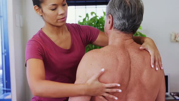 Physiotherapist giving shoulder massage to a senior man 4k