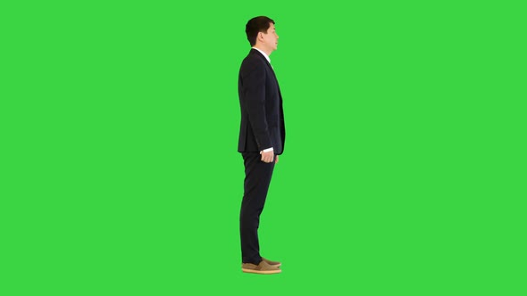 Asian Man Stands Adjusting His Suit and Crossing Arms on a Green Screen Chroma Key