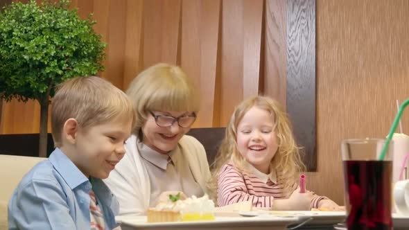 Kids Laughing while Having Dinner in Cafe with Grandmother