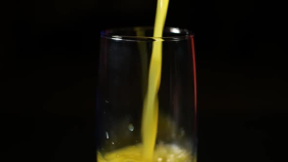 Orange Juice Being Poured in a Tall Glass on a Black Background.