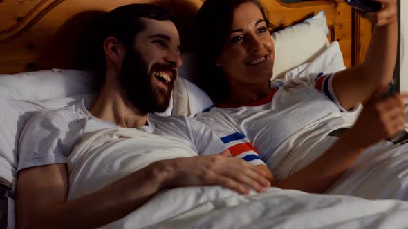 Couple taking selfie from mobile phone in bedroom