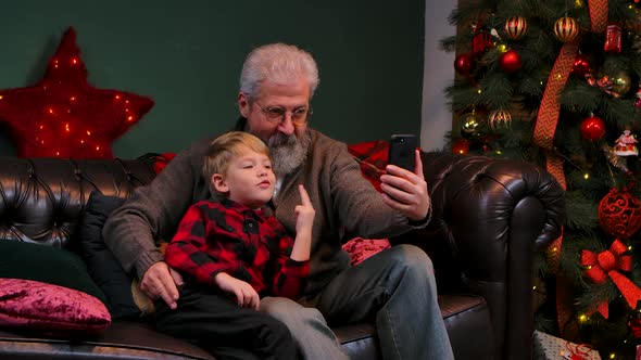 Elegant Old Man and Little Boy Talking on Video Communication on Smartphone