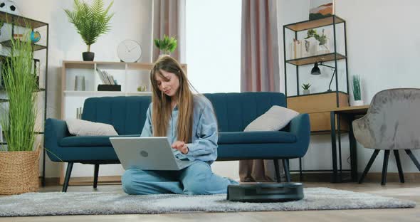 Girl which Resting on the Carpet at Home and Listening Music on Laptop