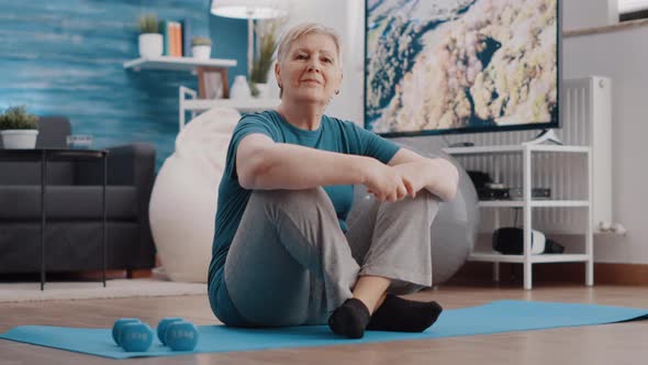 Portrait of Aged Woman Sitting on Floor Yoga Mat at Home