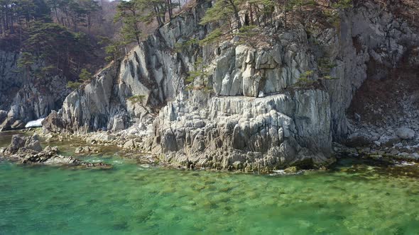 Aerial View of the Rocky Seashore of a Beautiful Bay with Transparent Water