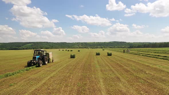 Side view of an agricultural tractor working in the field. Seasonal works for harvesting grass