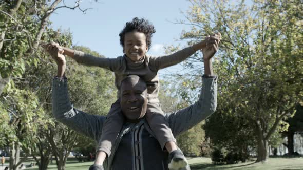 Bald African American Father Holding Son on Shoulders