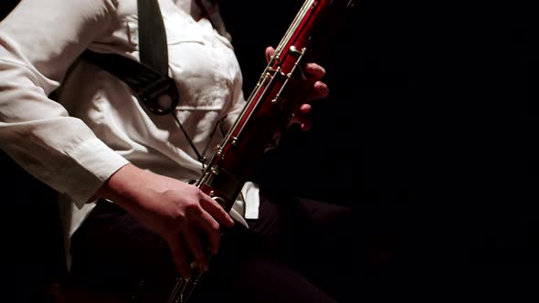 Female Musician Plays Jazz on Bassoon Tune in Studio on Dark Background Side View