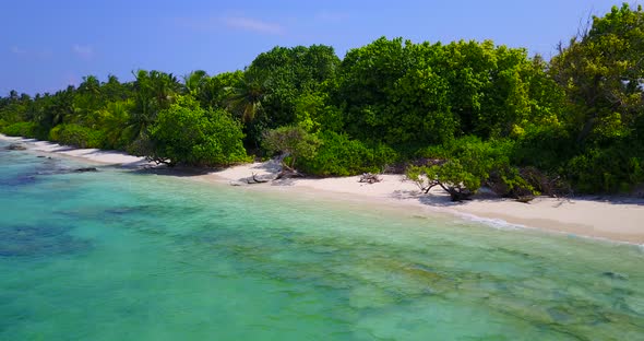 Tropical fly over abstract shot of a sandy white paradise beach and blue sea background in vibrant 4