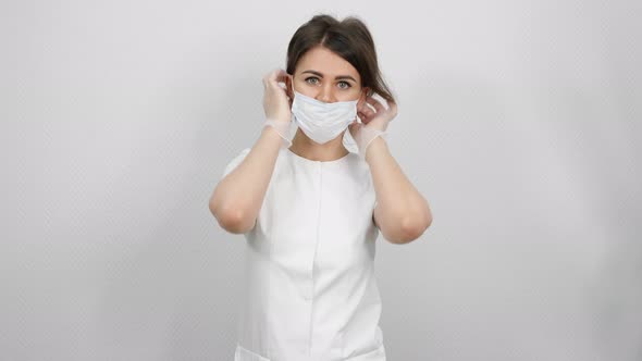 Woman Beautician Puts on White Protection Mask Close View