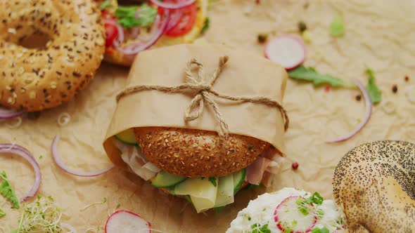 Bagels with Ham Cream Cheese Hummus Radish Wrapped in Brown Baking Paper Ready for Take Away