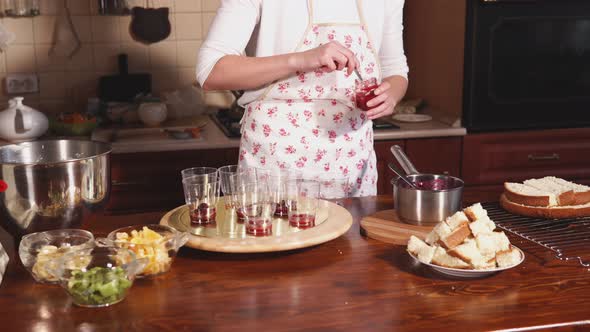 Chef Is Filling Glasses By Red Fruit Jam in a Home Kitchen, Standing Near Table