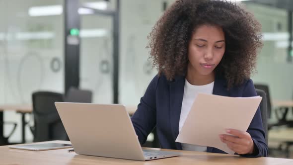 African Businesswoman with Laptop Having Success on Documents