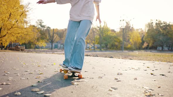 Slow Motion Closeup of a Girls Leg Rolling on a Board in an Autumn Park