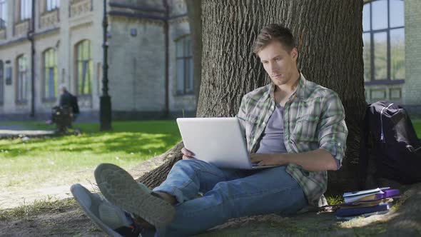 Guy Chatting Online in Social Media, Laughing and Relaxing in University Park