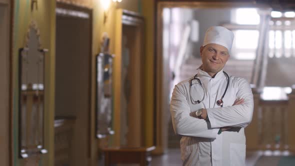 Portrait of a male smiling doctor satisfied with his work in a hospital corridor. The concept of med