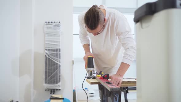 Carpenter in Protective Glasses Cuts Wood with Electric Jigsaw