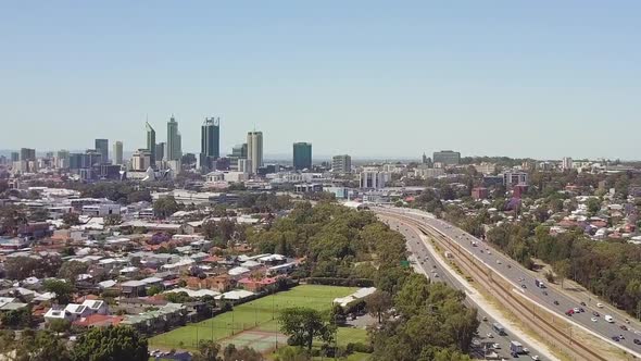 Aerial, freeway leading to high-rise buildings in distance, pedestal up, Perth, Australia