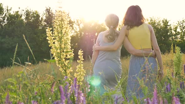 Back View of Senior Mother with Gray Hair with Her Adult Daughter in the Garden Hugging Each Other