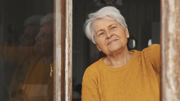 Mature Caucasian Woman with Grey Hair Watching Through the Window Copy Space Medium Closeup