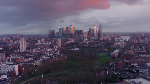 Slow drone shot towards Canary Wharf tower skyscrapers London from north mile end at sunset